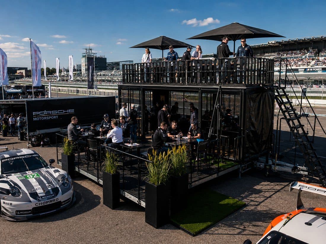 Gäste auf der Terrasse bei einem Motorsport-Event am Paddock.